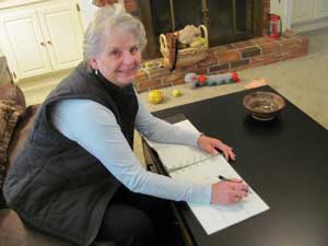 Carol Baker writing annual donations to national PD organizations